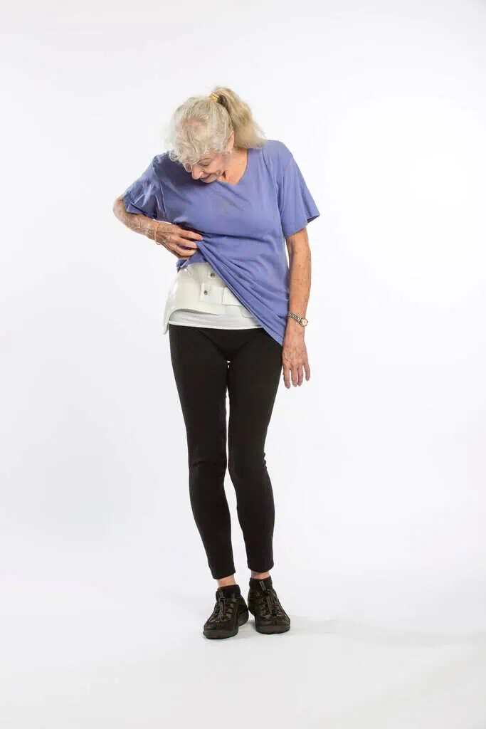 Elderly woman experiencing back pain, holding her lower back in discomfort, demonstrating the need for scoliosis and spinal health treatment.